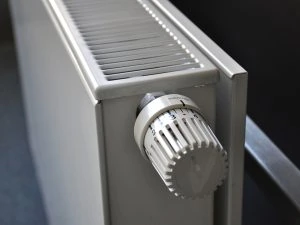 Close-up of a white radiator with a temperature control knob, showcasing numbers 1 to 5, exemplifies the precision offered by modern heating services, heating system installation, Ductless Heating and AC