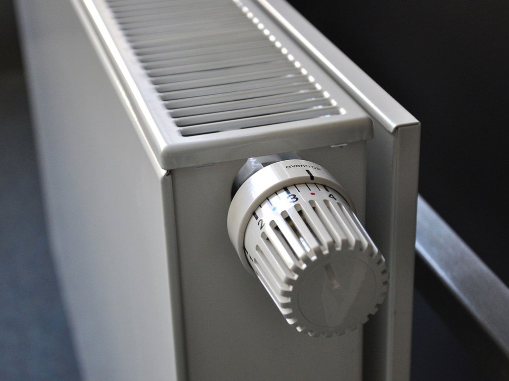 Close-up of a white radiator with a temperature control knob, showcasing numbers 1 to 5, exemplifies the precision offered by modern heating services.