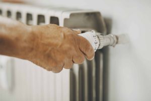 Close-up of a hand adeptly adjusting a radiator valve, showcasing precision in the repair heating system