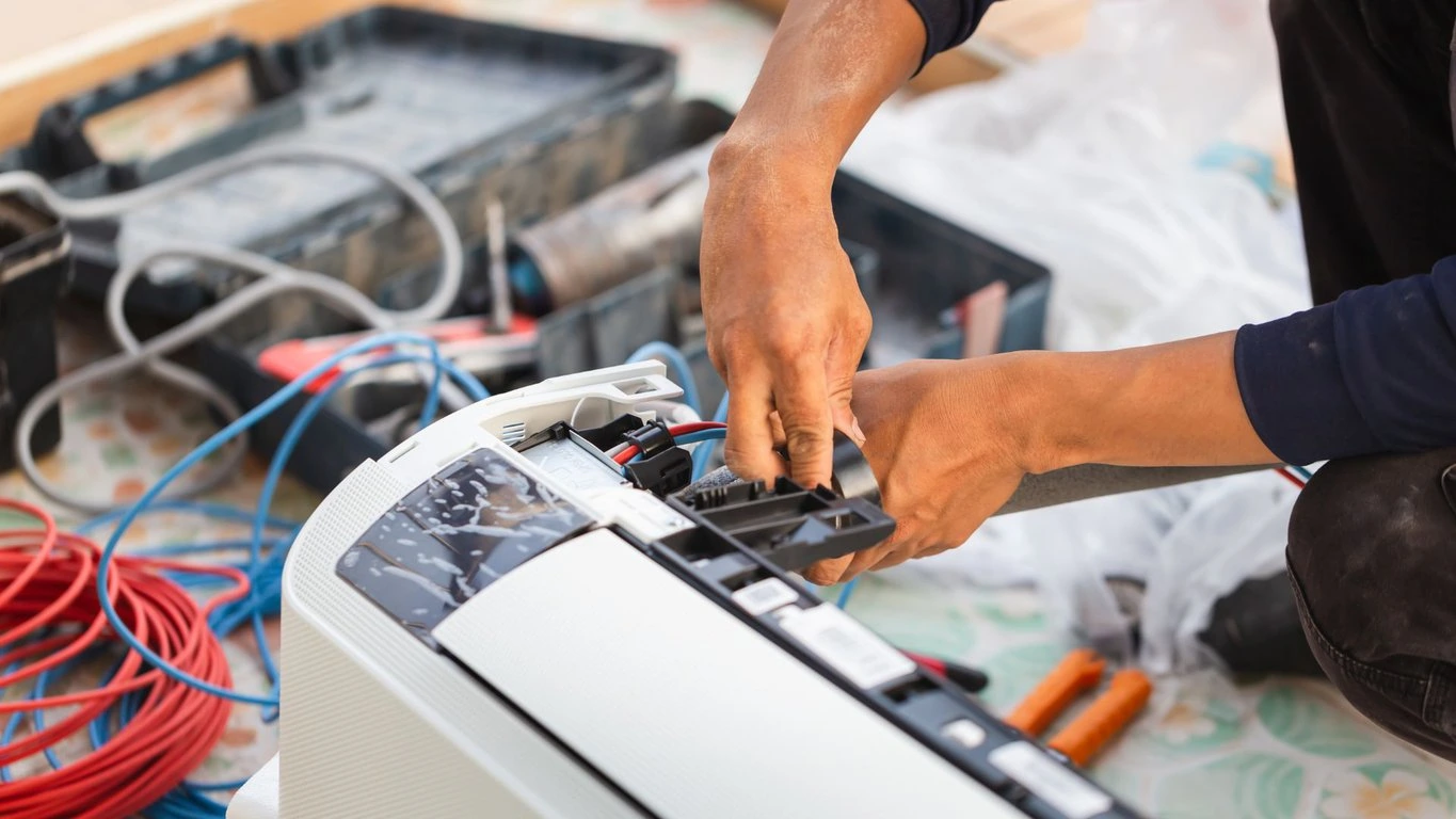 A man is working on an air conditioning unit.