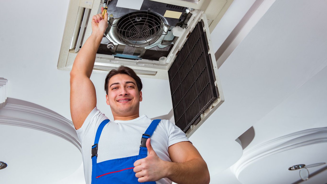 A man holding an air conditioner in his hands.