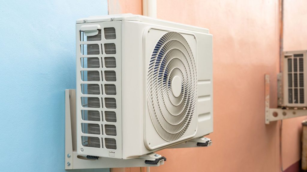 The HVAC system's outdoor unit is mounted on a vibrant wall, featuring sections of blue and peach.