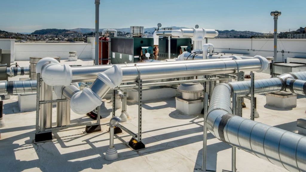 A rooftop with complex metal ventilation ducts and pipes against a clear sky serves as a testament to the intricacies involved in furnace repair in Mississauga.