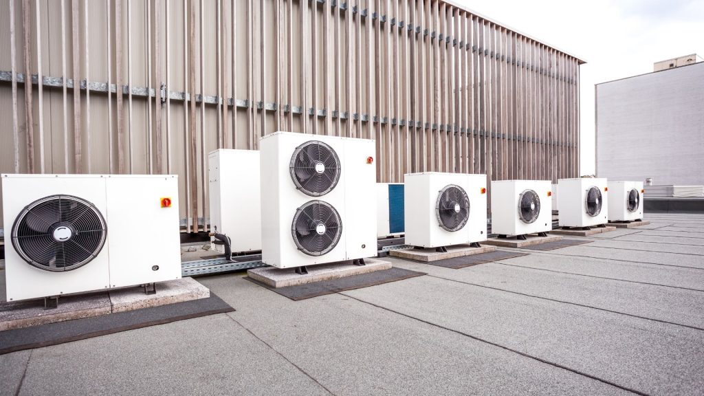 A row of industrial HVAC units sits on a flat rooftop, with the expansive wall of a large building in the background, showcasing the robust infrastructure that supports furnace repair needs in Mississauga and Brampton.