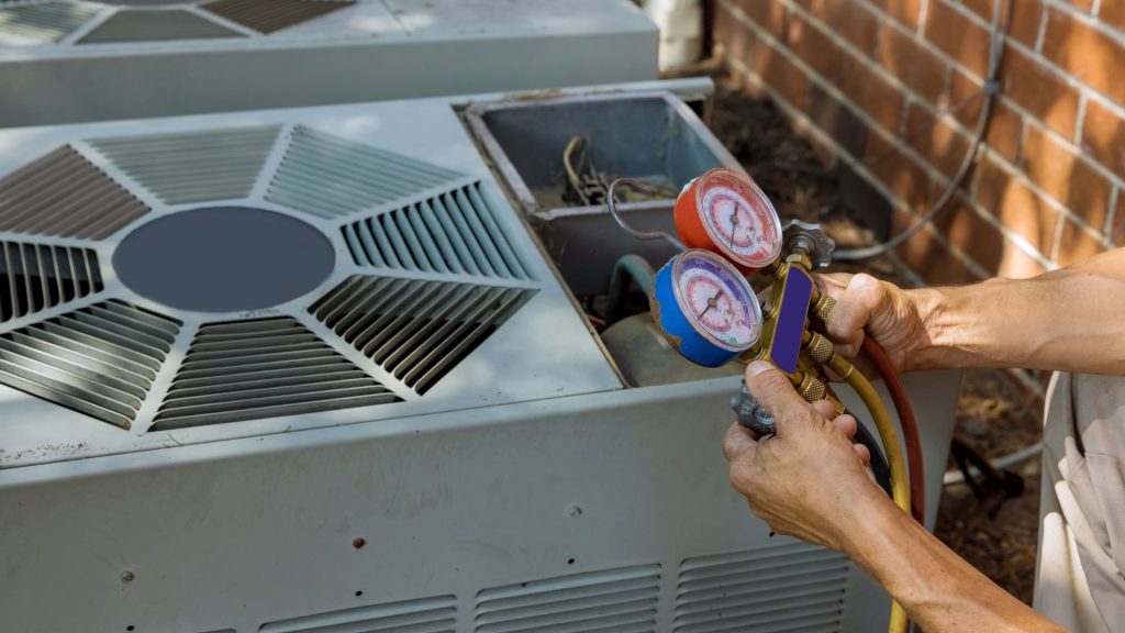 A skilled technician from the HVAC company meticulously uses pressure gauges to service an outdoor air conditioning unit.