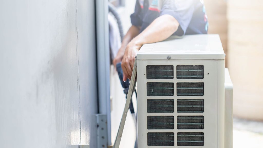 A technician diligently works on an outdoor air conditioning unit attached to a building wall, ensuring expert air conditioner repair Mississauga.