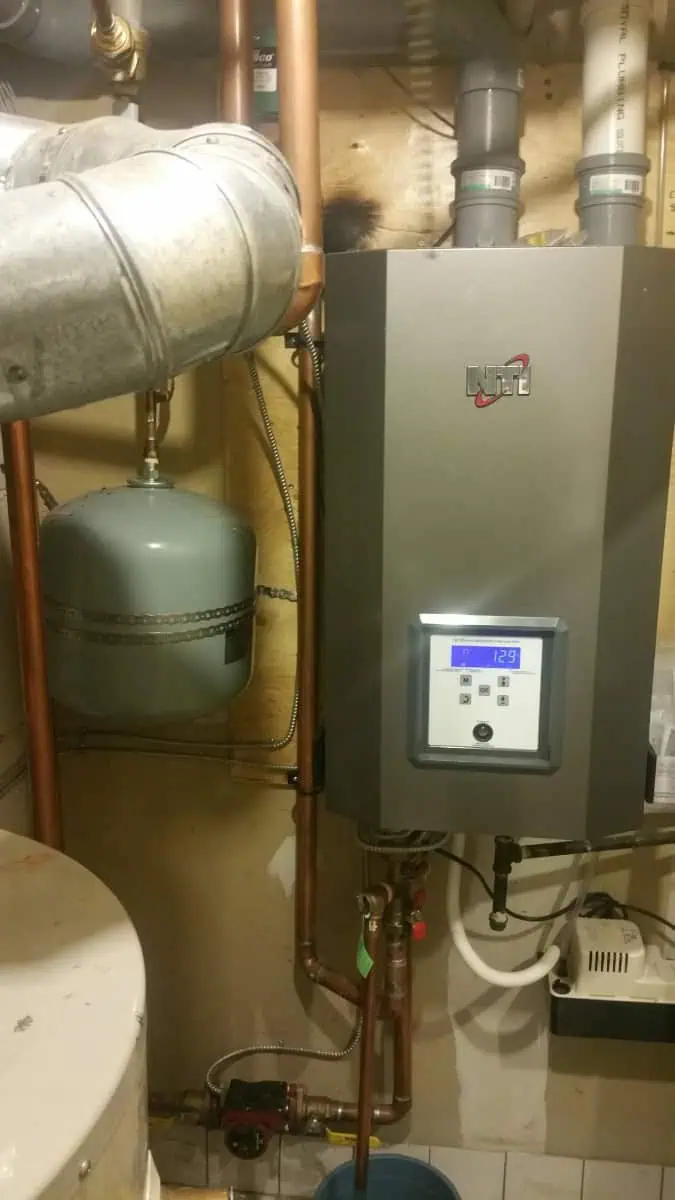 A water heater system with pipes and a pressure tank is installed in a utility room. An electronic display on the heater shows a reading. For related services like Mississauga furnace repair, trusted local experts ensure your home's heating efficiency.