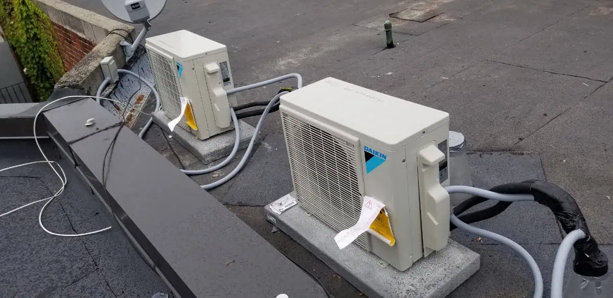 Two Daikin HVAC outdoor units are expertly mounted on a flat rooftop by an experienced HVAC contractor in Brampton, Canada, with well-connected electrical and piping systems.