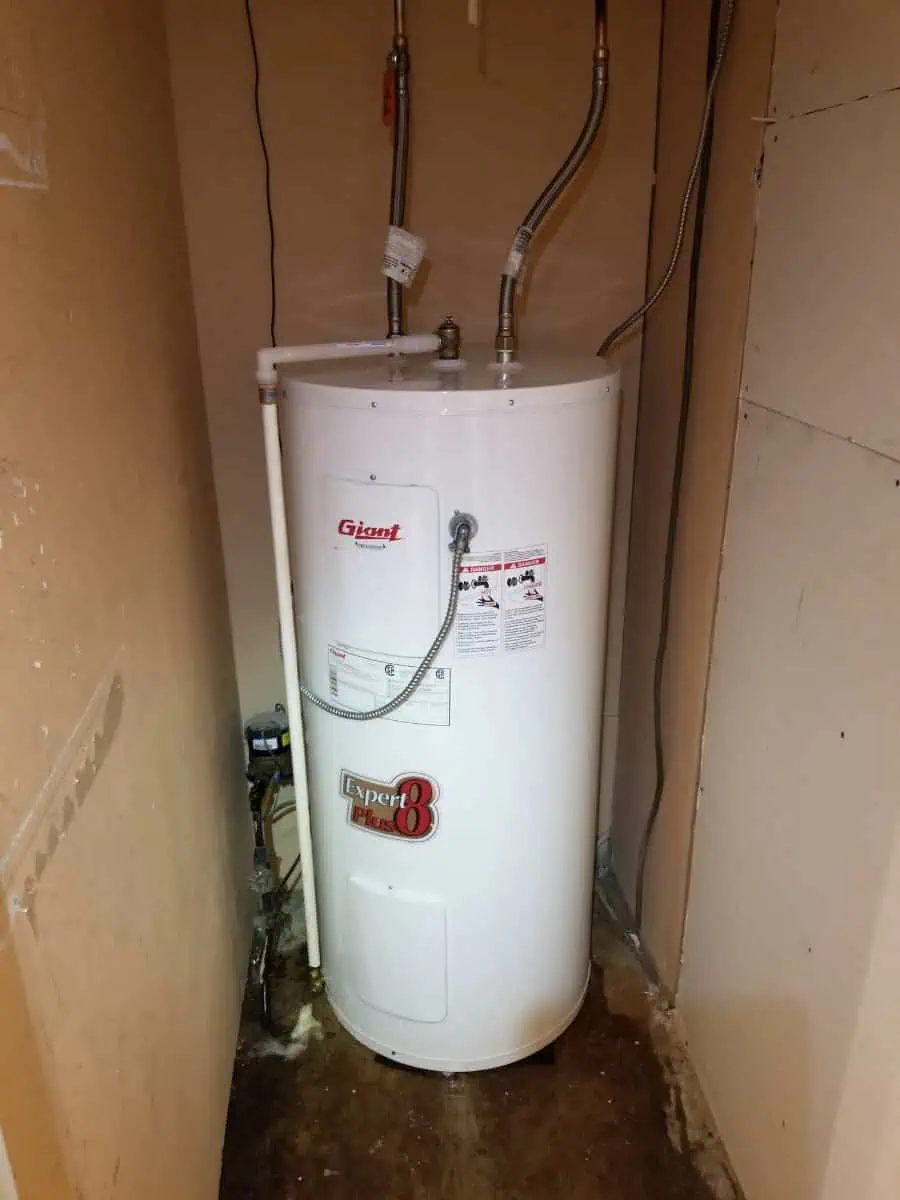 A white electric water heater is installed in a small utility closet with exposed pipes and wiring, expertly integrated as part of the full HVAC Milton system.