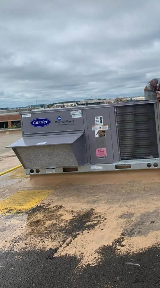 The rooftop HVAC unit, expertly installed by a leading HVAC contractor in Brampton, Canada, stands prominently on the building under a cloudy sky, with visible labels and its surrounding area clearly showcased.